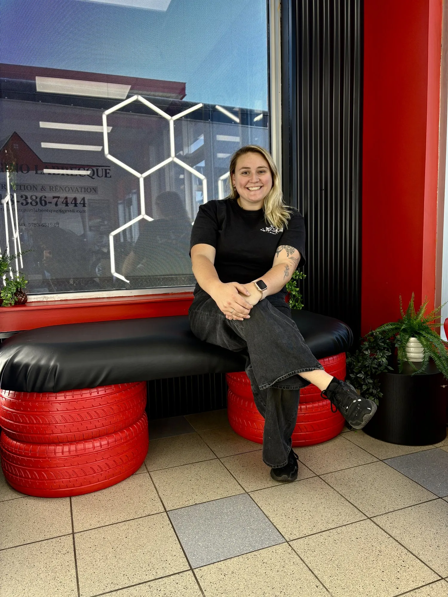 Esther assise sur la banquette en pneus rouges qu’elle a fabriquée