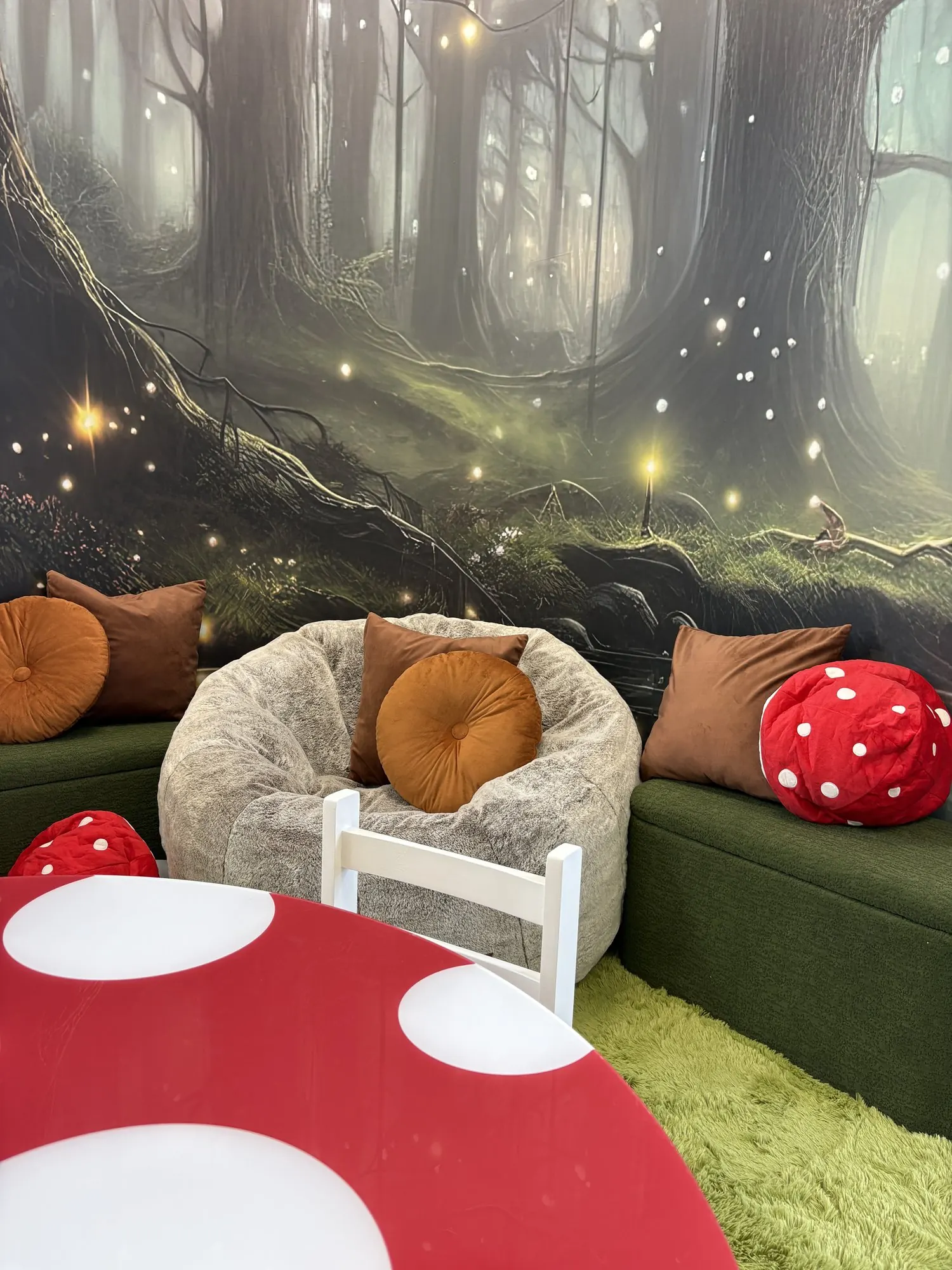 Table en champignon et fauteuils devant une murale de forêt lumineuse