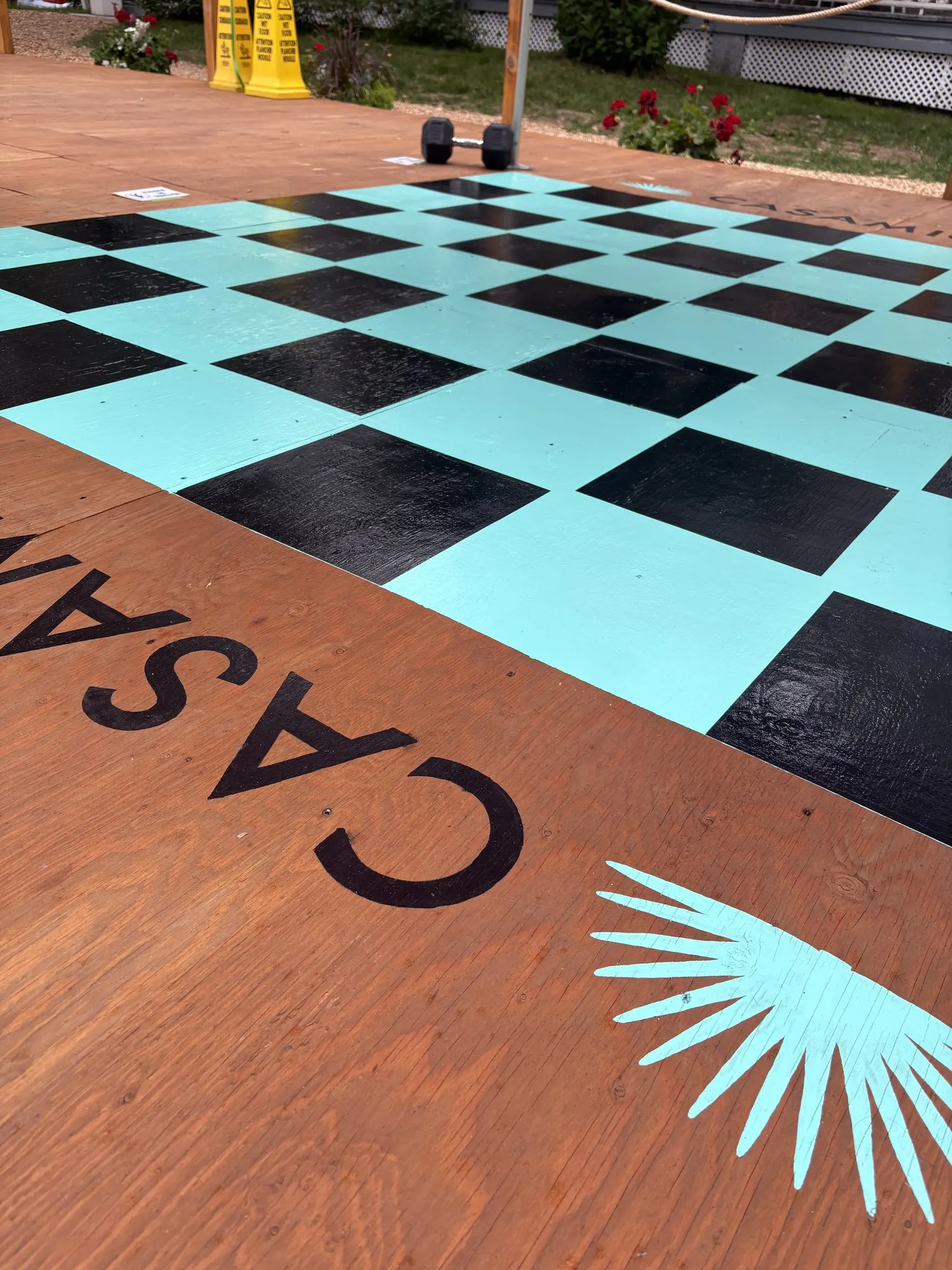 Damier géant turquoise et noir en vinyle sur plateforme en bois, avec logo de la marque