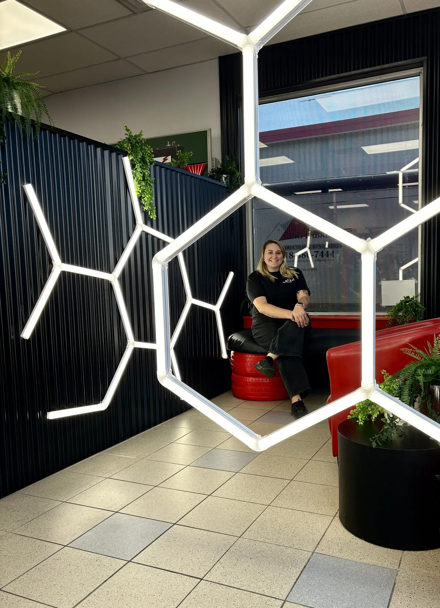 Esther assise sur la banquette de la salle d’attente, sous les néons hexagonaux