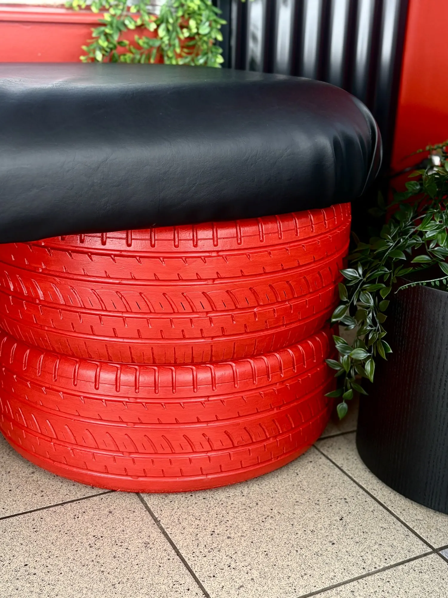 Détail de la banquette : pneus empilés repeints en rouge et assise en cuir noir