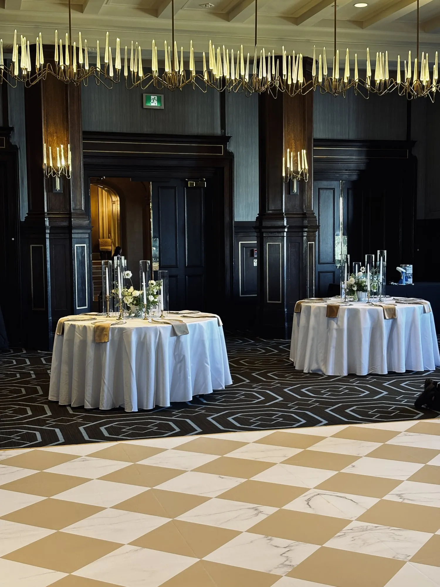 Plancher en damier effet marbre posé dans une salle de réception, tables nappées de blanc