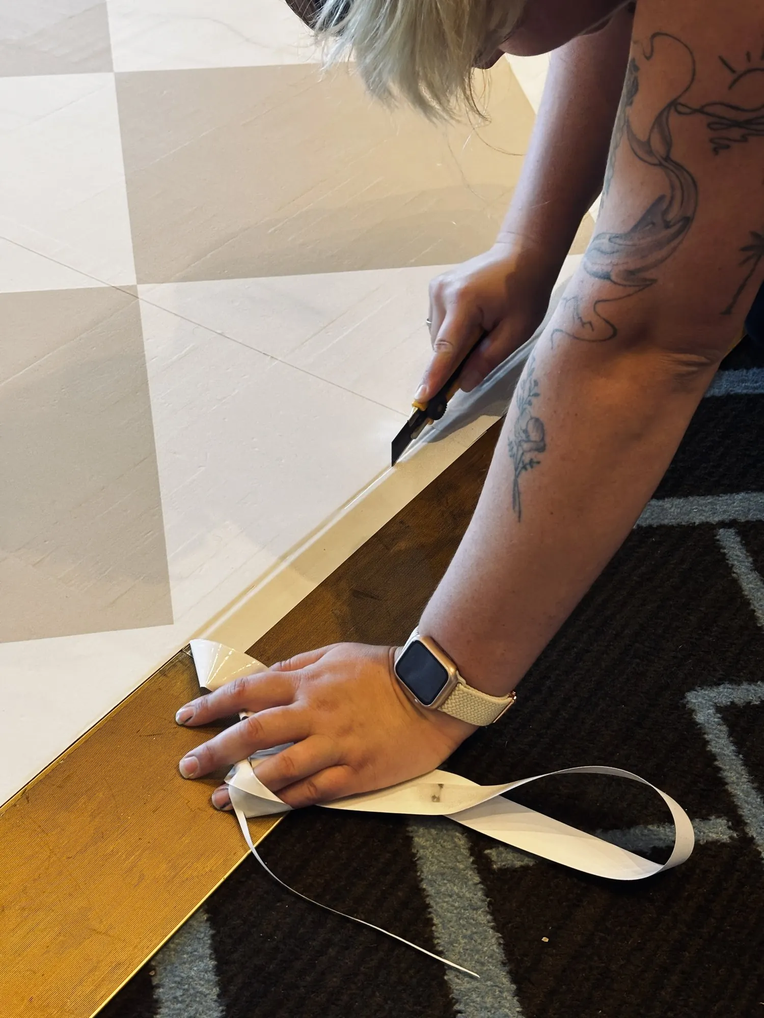 Découpe au cutter d’un vinyle de plancher en damier lors de la pose