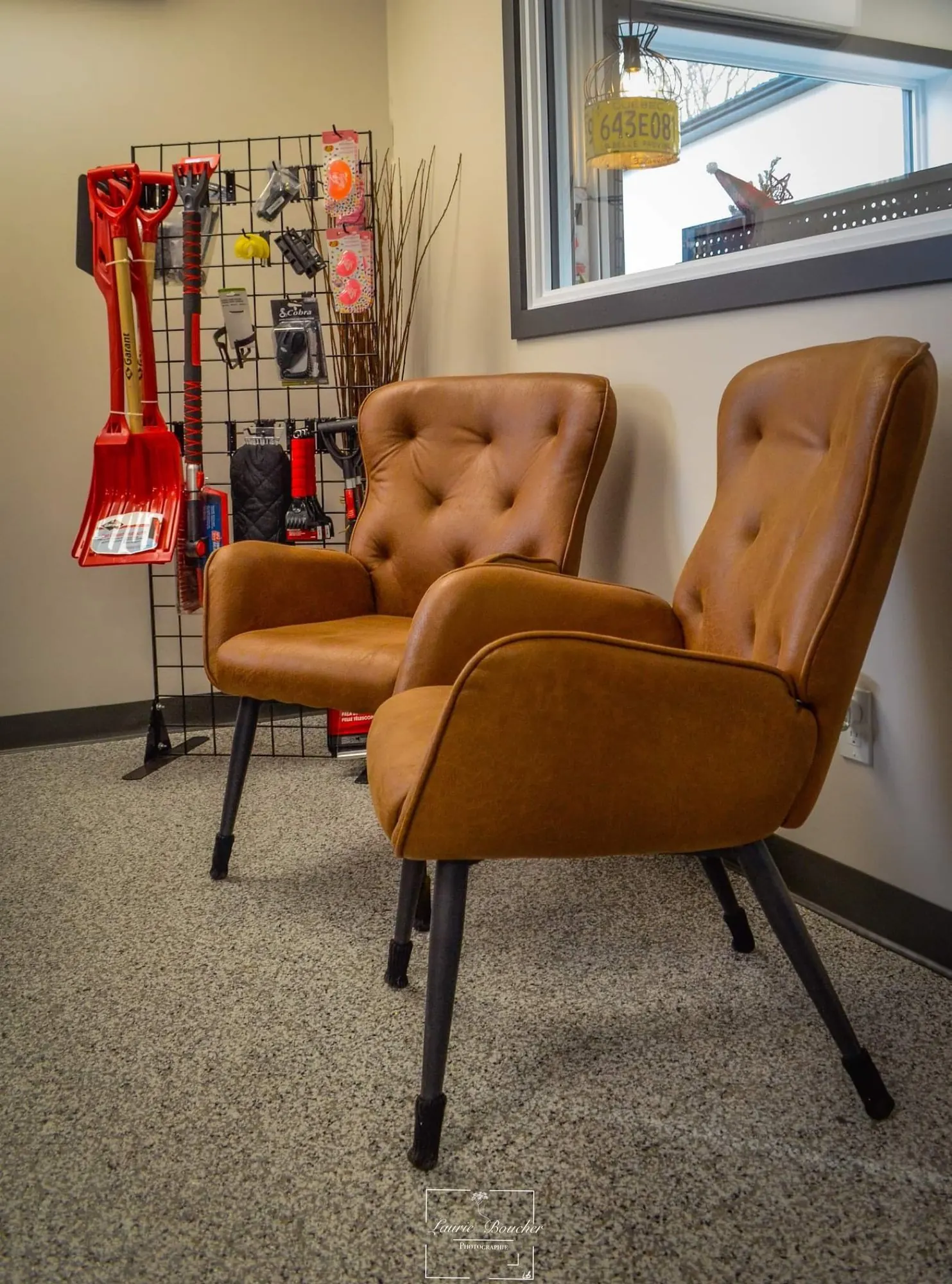 Coin salon avec fauteuils en cuir et présentoir mural d’outils, décor de garage