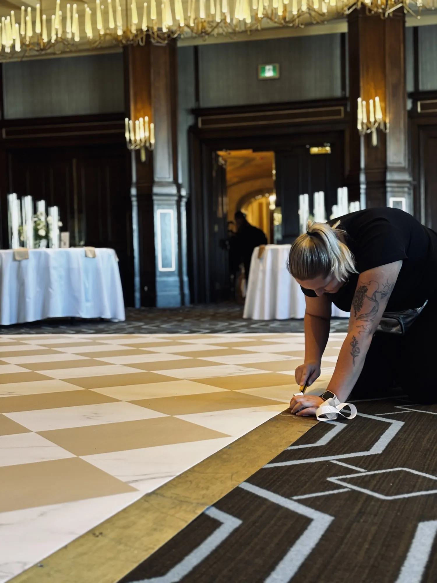 Esther finissant la pose du plancher en damier dans la salle de réception