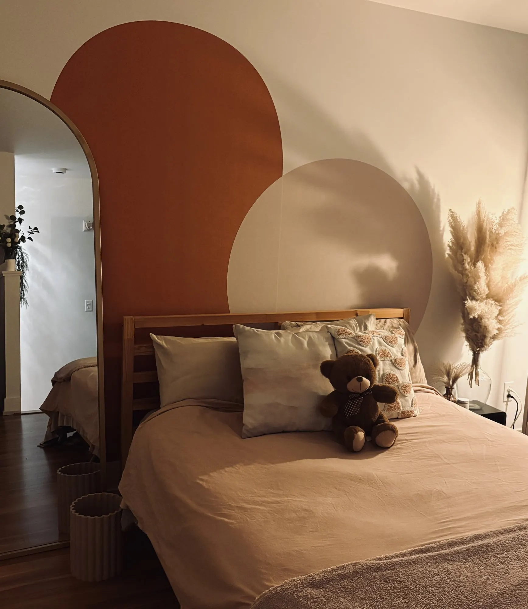Chambre avec murale aux formes d’arche terracotta et beige derrière le lit