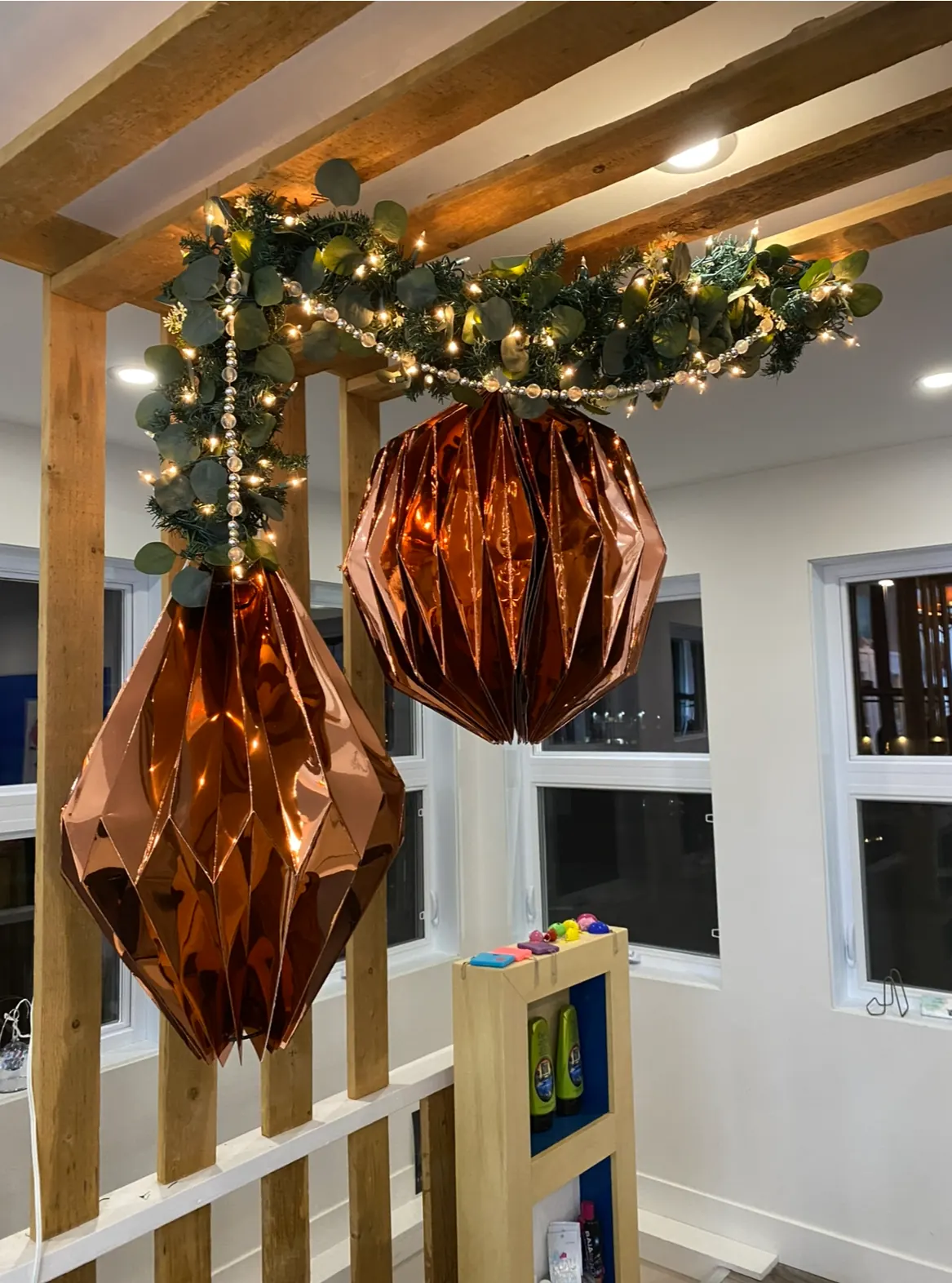 Décor de Noël avec guirlande lumineuse et grandes suspensions géométriques cuivrées